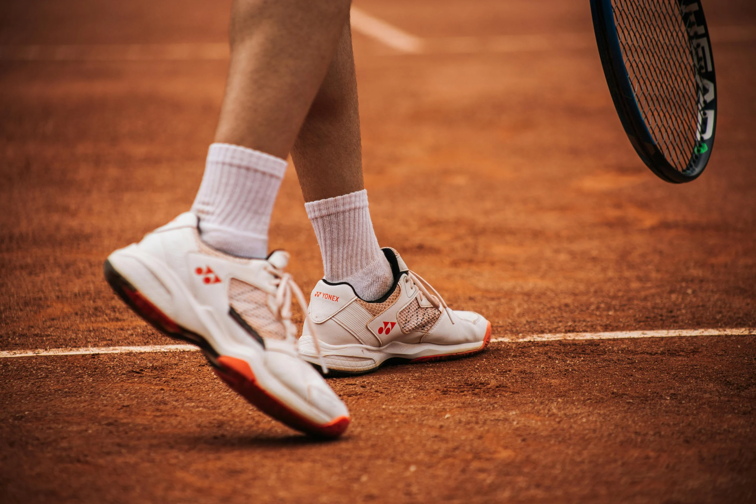 Close-up van tennisschoenen op een gravelbaan